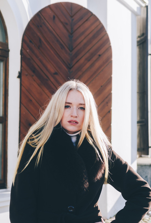 Young beautiful blonde girl staying near the wood doorの写真素材