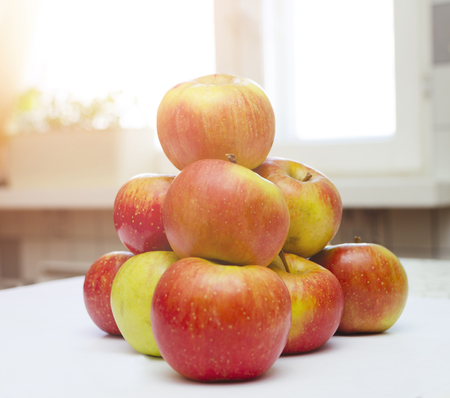 Red yellow apples on the home kitchen table with soft light of sun in summer dayの写真素材