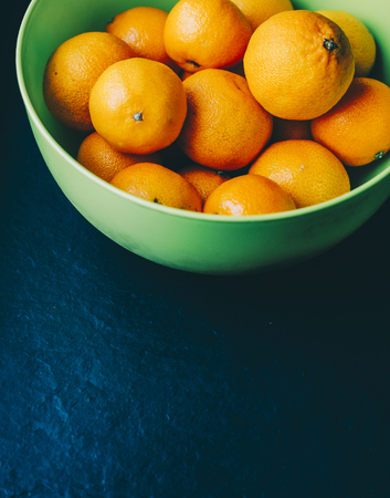 Mandarins in green plate on the black backgroundの写真素材