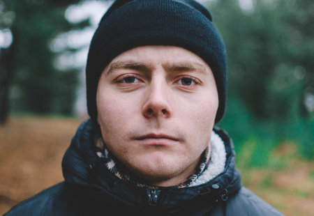 Handsome young man in winter clothes with a backpack on the background of an autumn forest.