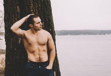 Young muscular man near the tree on lakeの写真素材