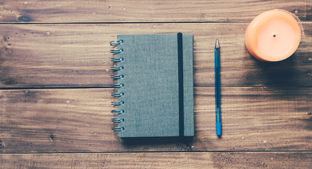 Notebook and candle on the vitnage wood table backgroundの写真素材