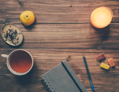Cup of tea, note, candle, pen and other elements on wooden tableの写真素材