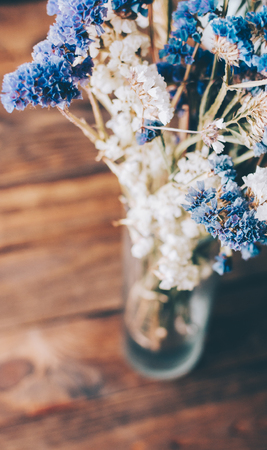 Blue and white flowers in vase on wooden tableの写真素材