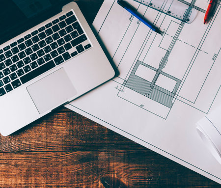 Top view of drawing with architecture sketch, laptop and pens on creative workspace