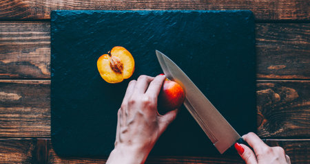 Woman cute the peach on kitchen table