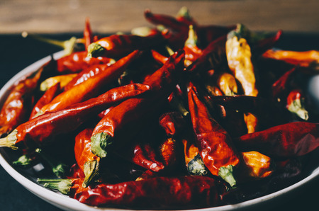 Red dry pepper on the plate on black stone backgroundの写真素材
