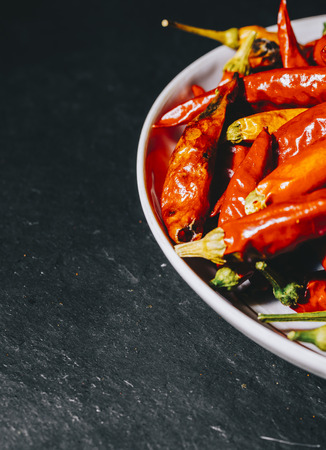 Red dry pepper on the plate on black stone backgroundの写真素材