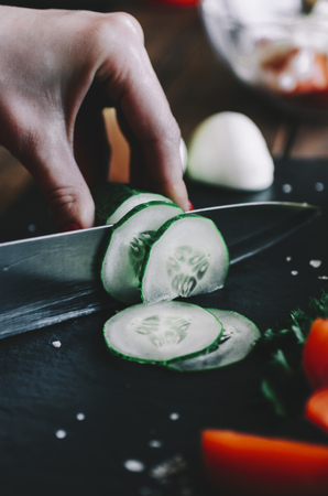 Woman sliced the cucumber on the kitchen tableの写真素材