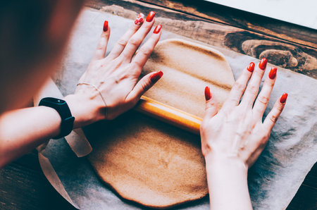 Making dough by female hands on wooden table background