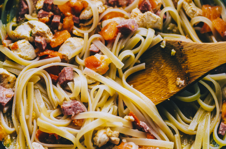Pasta with meat and tomato in pan on home kitchenの写真素材