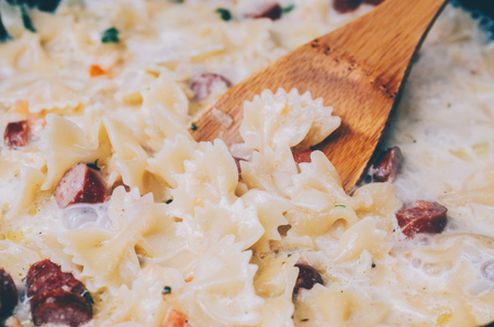 Pasta farfalle with sausage salami in milk sauceの写真素材