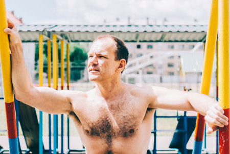 40s man in city park fit on barsの写真素材