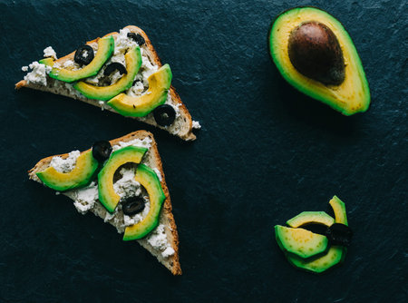 Sandwich with chesse and avocado on black stone background