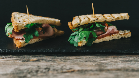 Two sandwiches on black stone background on kitchen tableの写真素材