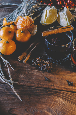 Glasses, cup of red hot drink. Mulled wine on wooden background with christmas spices,orange slice, close up.の写真素材
