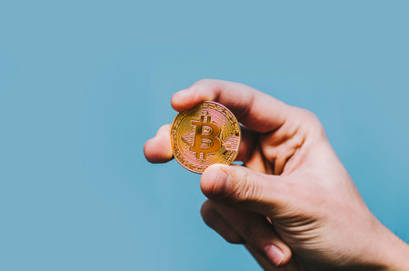 Bitcoin in man hand on isolated blue background