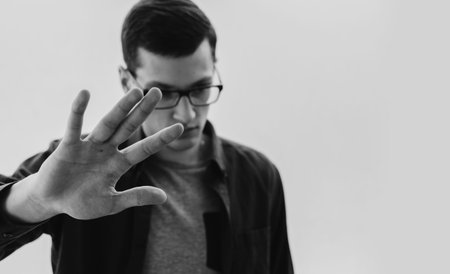 Young man in glasses hide face by the handの写真素材