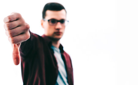 Young man in glasses with thumb down on white background