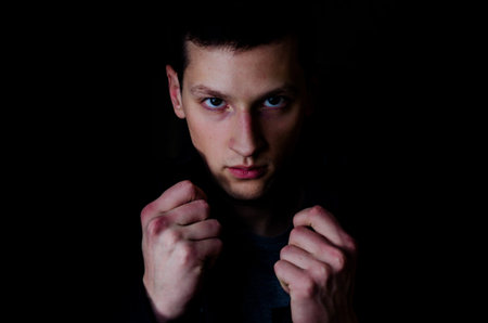 Portrait of the young man in coat on black background