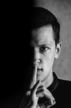 Attractive man with finger on lips making silence gesture. Shh!!!