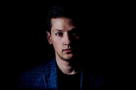 Young man in jacket on black background, low key portrait