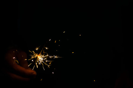 Sparkler fire in hand on black isolated background