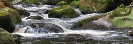 Wide small waterfalls with big pebbles and forestの写真素材