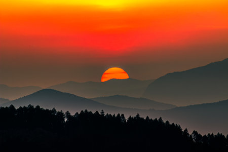 The sun rising over the mountains and turning the sky red.の写真素材