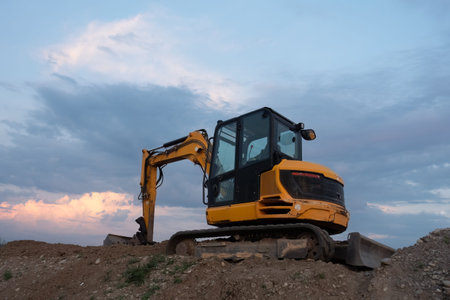 A small crawler excavator with a blade standing on top of a pile of dirt