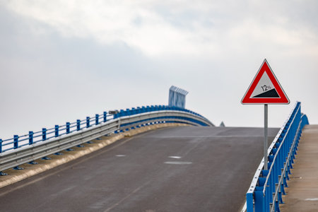 A road bridge with a slope. The slope of the road is indicated by a traffic sign.の写真素材