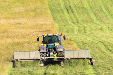 Rear view of a tractor mowing a meadow.の写真素材