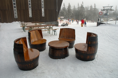 Janske Lazne Czech Republic February 17 2015: Unique chairs and table made of old wooden barrels standing on snow at restaurant nearby gondola lift station on top of Cerna Hora mountain in Karkonosze mountains. Unidentified people visible.のeditorial素材