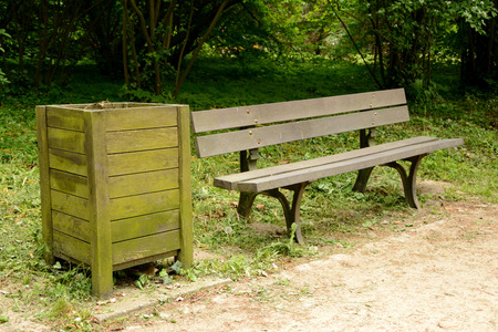 Old wooden dustbin and bench standing at path in park.の写真素材