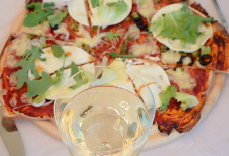Glass of white wine close up and blurred pizza in backgroundの写真素材