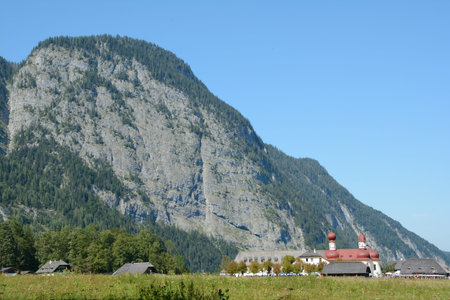 Schonau am Konigssee, Germany - August 30, 2015: St. Bartholoma church and mountain at Koenigssee lake nearby Schonau am Konigssee in Germany. Unidentified people visible.のeditorial素材