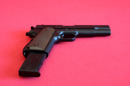 Airsoft gun and magazine on red fabric.
