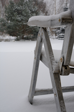 Old vintage wooden chair in snow. Shallow depth of field.の写真素材