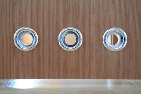 Round silver vents in brown wooden bathroom door.