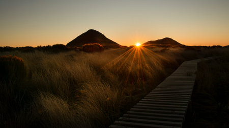 Pouakai Circuit of Egmont National Park at dawn with sun starbursts shining through the mountain...