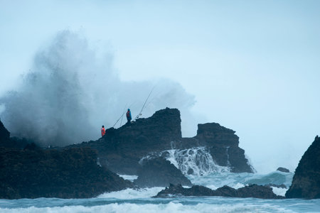 Fishing at the Piha beach with big waves crashing on the rocks