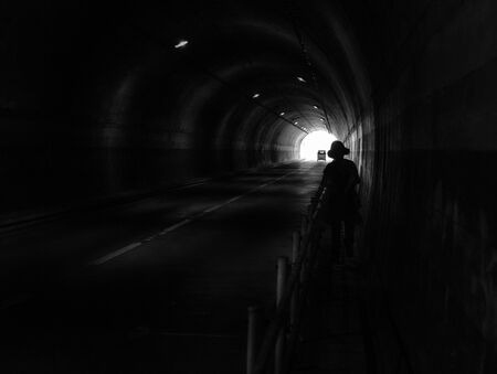 Human and car silhouette in the dark tunnel. Light at the end of the tunnel.  の写真素材