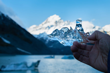 Tourist holding an ice against the mighty Mt Cook and iceberg-speckled Hooker lakeの写真素材