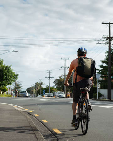 Cycling to work on the road with out-of-focus people doing their morning walk. Vertical format.の写真素材