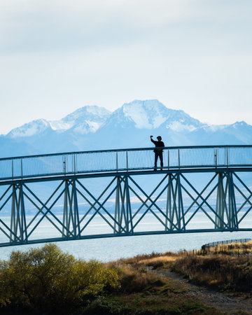 Tourist taking selfie photo on the Lake Tekapo Footbridge with Southern Alps in the background,...