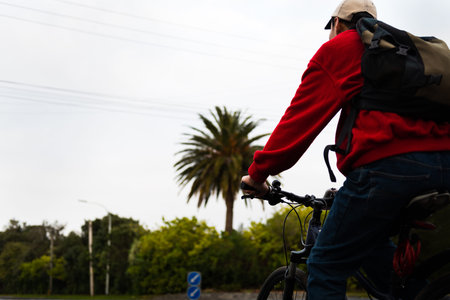 A cyclist riding to work on the urban street with out-of-focus power lines overhead