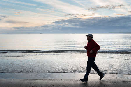 Man running on the beach at sunriseの写真素材