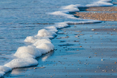 Sea wave foams on the beach at sunrise, Milford Beach, Aucklandの写真素材