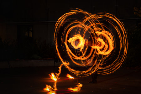 Street artist juggling with burning Hoop at fire performance. Long exposure image of abstract fire light painting.のeditorial素材