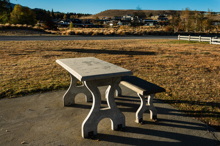 Outdoor concrete picnic table and bench under the morning sun in autumn, Lake Tekapo, South Island.